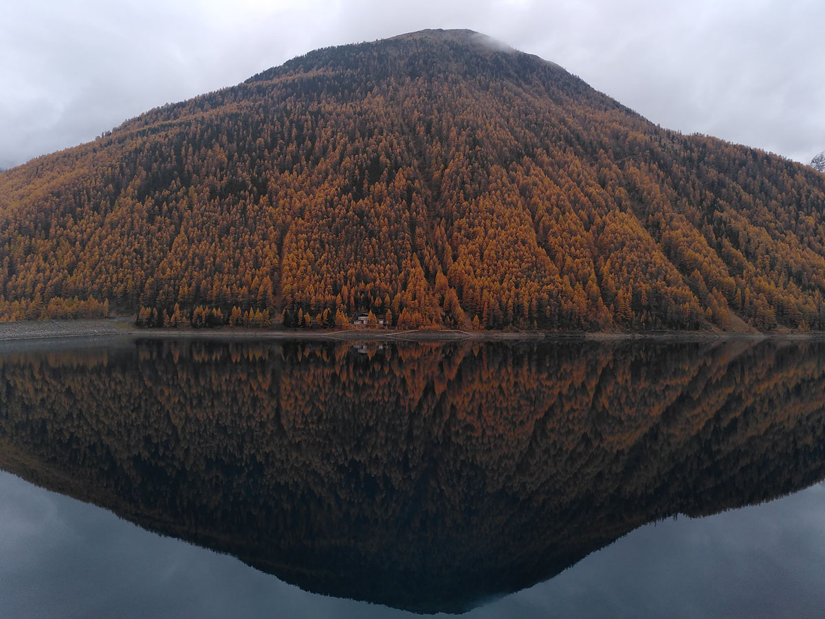 Bergsee mit bewaldetem Berg der sich im Wasser spiegelt